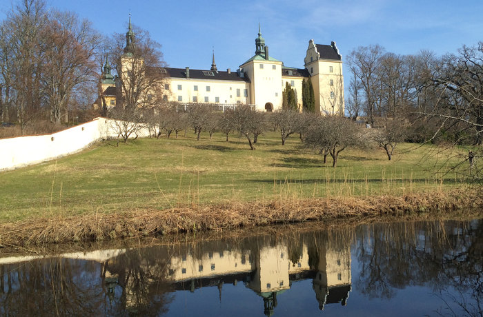 Tyresö slott i mars med spegling i vattnet.