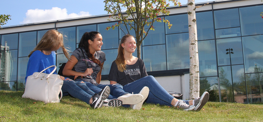 tre studenter sitter på gräsmattan